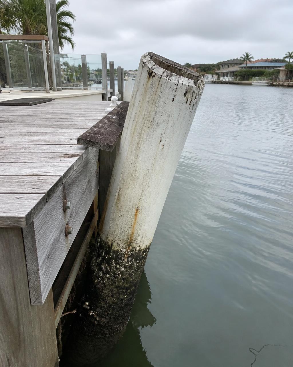 Leaning damaged pontoon pile on a Gold Coast canal before straightening